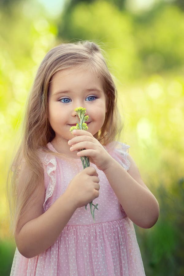 A Girl In A Pink Dress With Large Flowers On Her Head Looks At The Camera Stock Image Image 