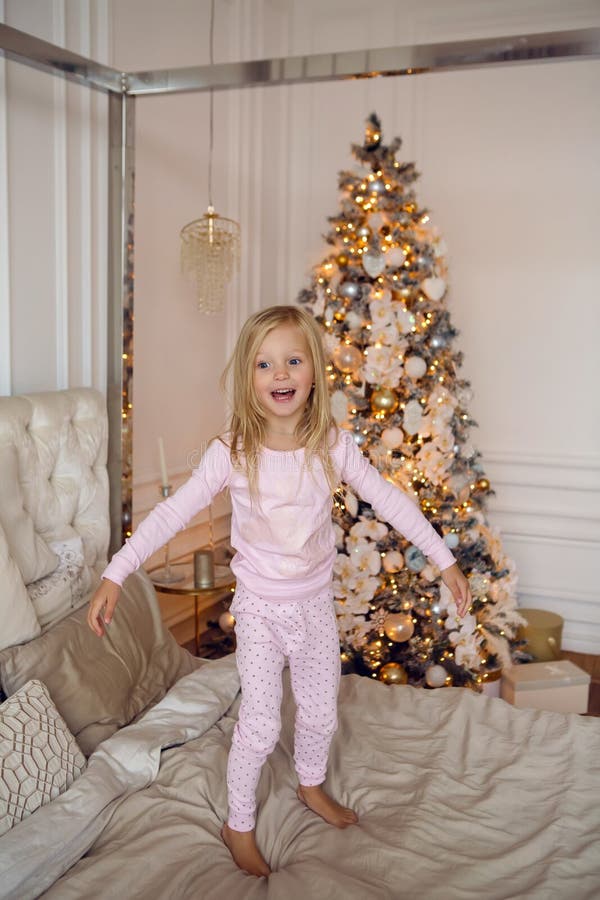 Girl in pink pajamas having fun on a large bed on Christmas day stock photography Girl in pink pajamas having fun on a large bed on Christmas day stock photography