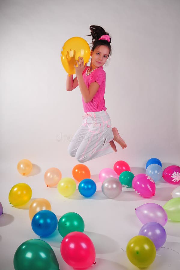Girl in a pink shirt and jeans jumping in the studio