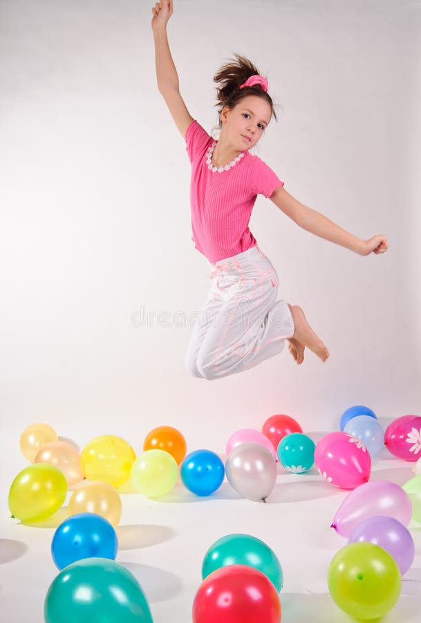 Girl in a pink shirt and jeans jumping in the studio