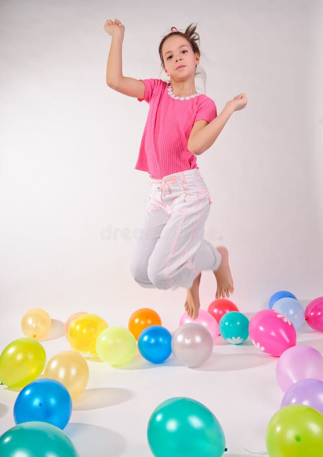 Girl in a pink shirt and jeans jumping in the studio