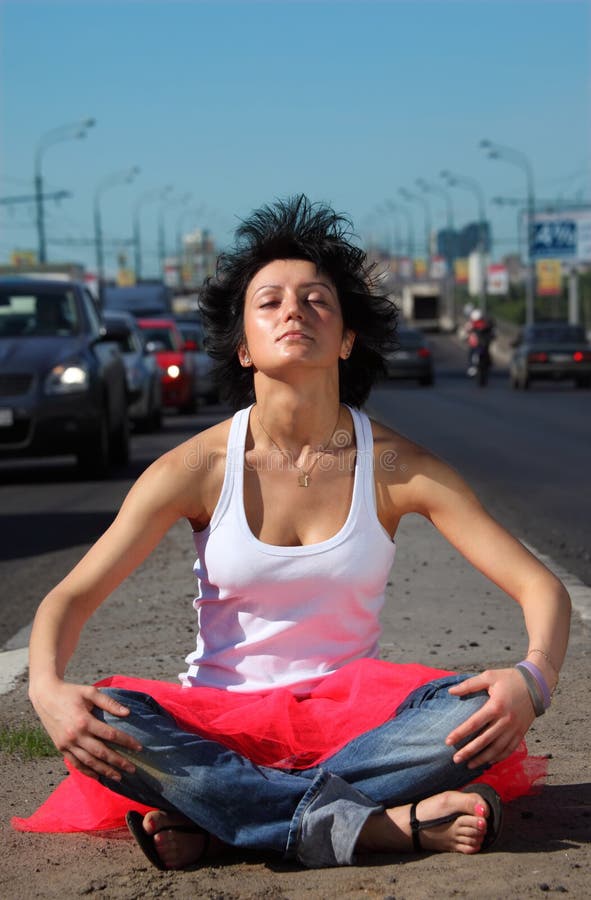 Girl in pink skirt meditates on highway middle