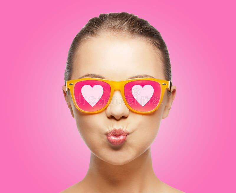 Love, happiness, valentines day, face expressions and people concept - portrait of teenage girl in pink sunglasses with hearts blowing kiss. Love, happiness, valentines day, face expressions and people concept - portrait of teenage girl in pink sunglasses with hearts blowing kiss.