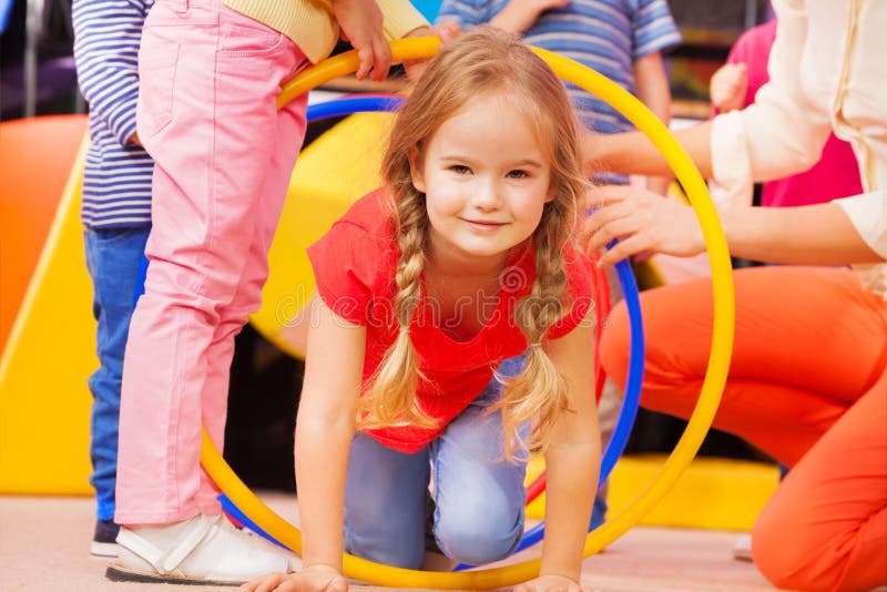 Girl play a game in kindergarten crawl though hoop royalty free stock photo Girl play a game in kindergarten crawl though hoop royalty free stock photo