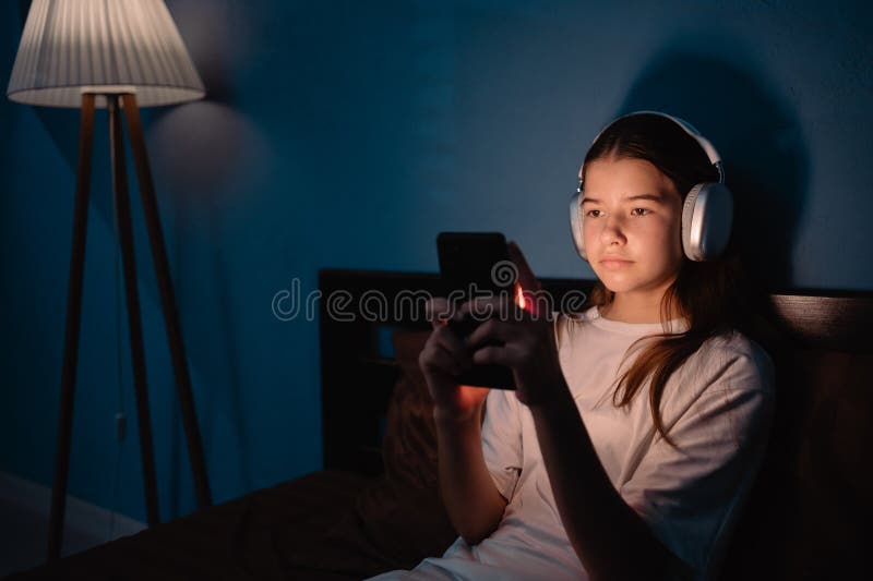 Girl play games at night. Portrait of a female teenage using mobile phone in room. Teen girl addicted stock images