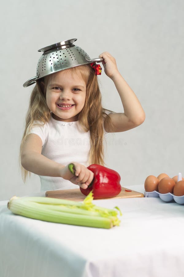 Baby boy playing on kitchen counter with strainer over his head Stock Photo