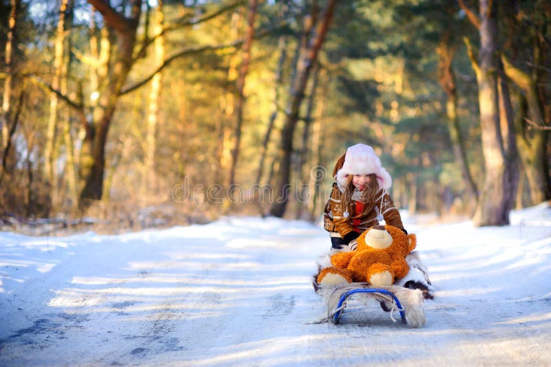 Girl playing and having fun in the winter forest at sunset