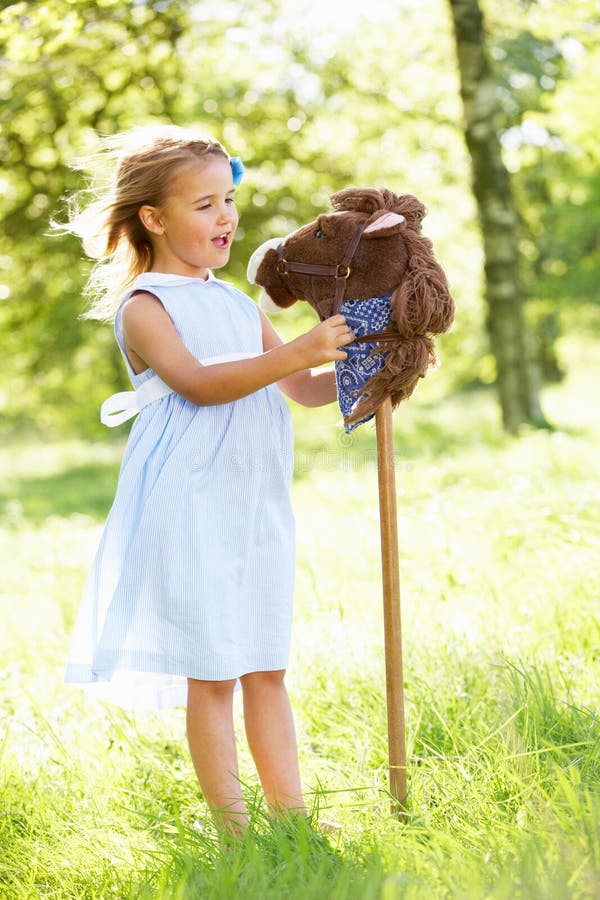 Girl Playing With Hobby Horse In Summer Field