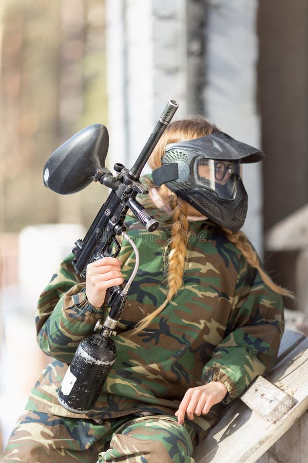 Girl Playing Paintball in Overalls with a Gun. Stock Photo Image of
