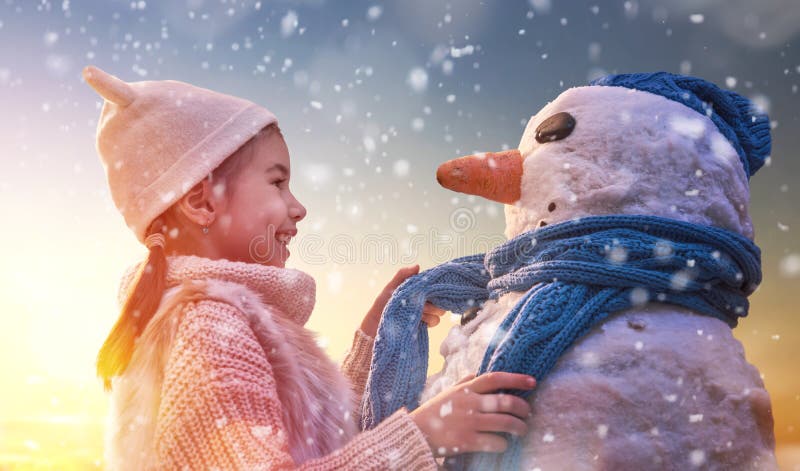 Fată care se joacă cu un om de zăpadă stock images
