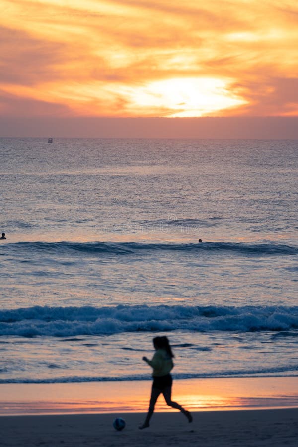 Girl On The Shore Playing With Sand On A Background Of Sea