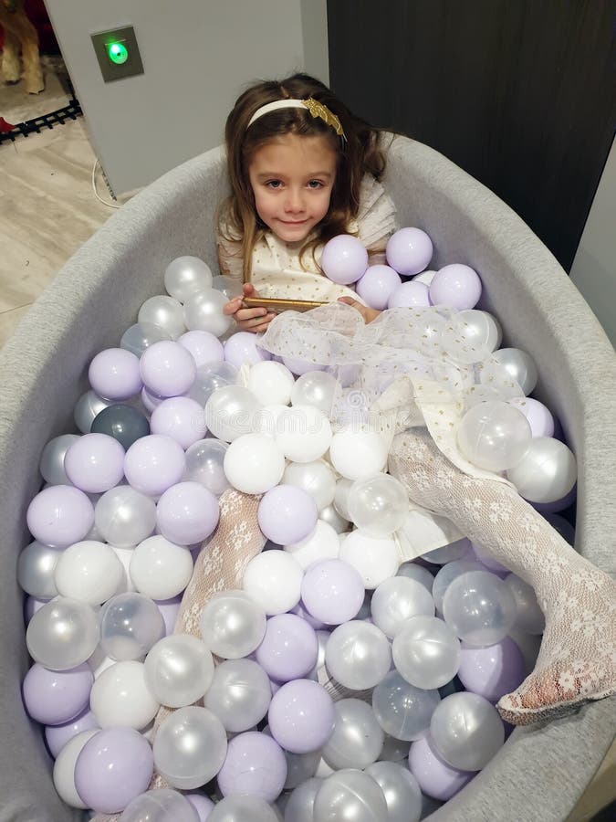 girl plays in a white and gray indoor ball pit