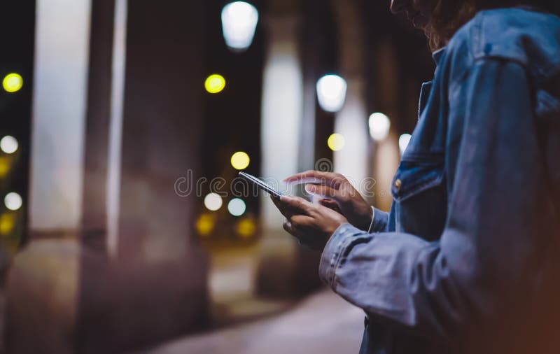 Girl pointing finger on screen smartphone on background illumination glow bokeh light in night atmospheric city, hipster using royalty free stock photography Girl pointing finger on screen smartphone on background illumination glow bokeh light in night atmospheric city, hipster using royalty free stock photography