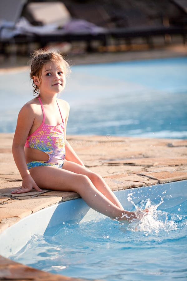 Girl by pool with legs in the water