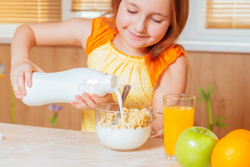 Girl pours milk for healthy breakfast