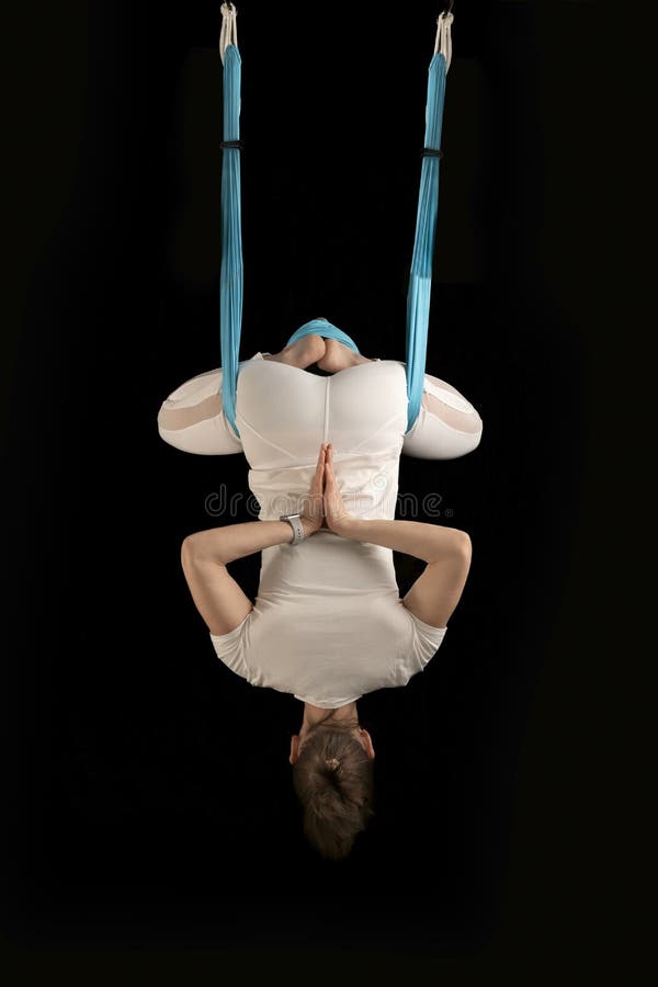 Girl practices anti-gravity yoga upside down. Yoga teacher demonstrates inverted asanas during fly yoga royalty free stock photo