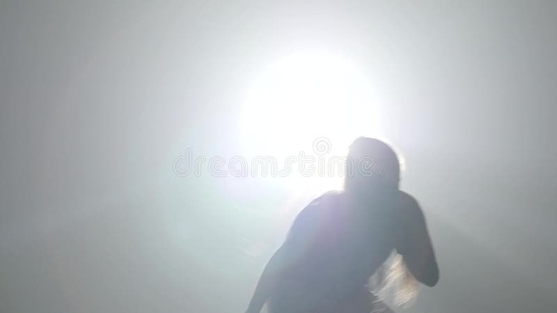 Girl practicing capoeira in ray of spotlight in studio. Close-up slow motion.