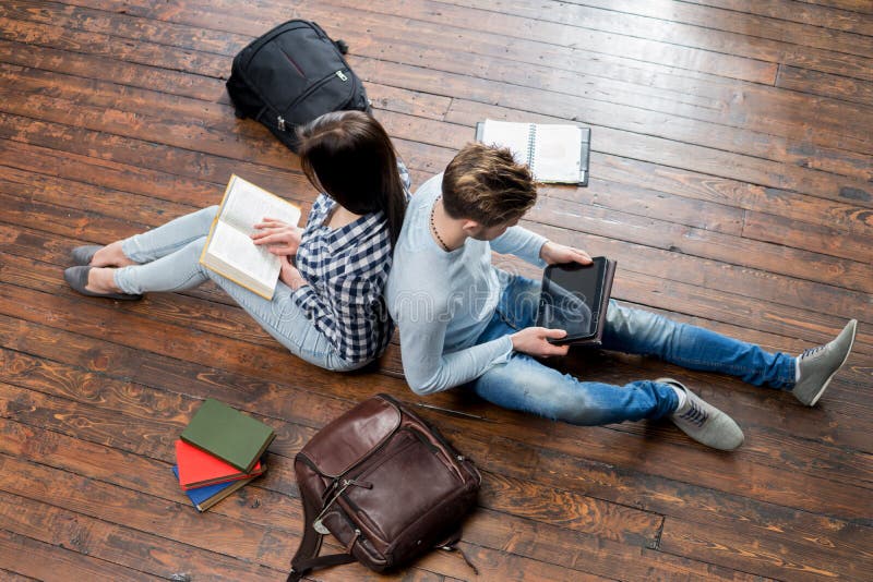 Girl reading a book and boy using a tablet royalty free stock photos