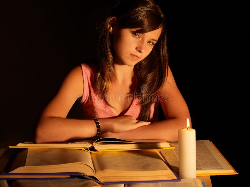 Girl reading book with candle.