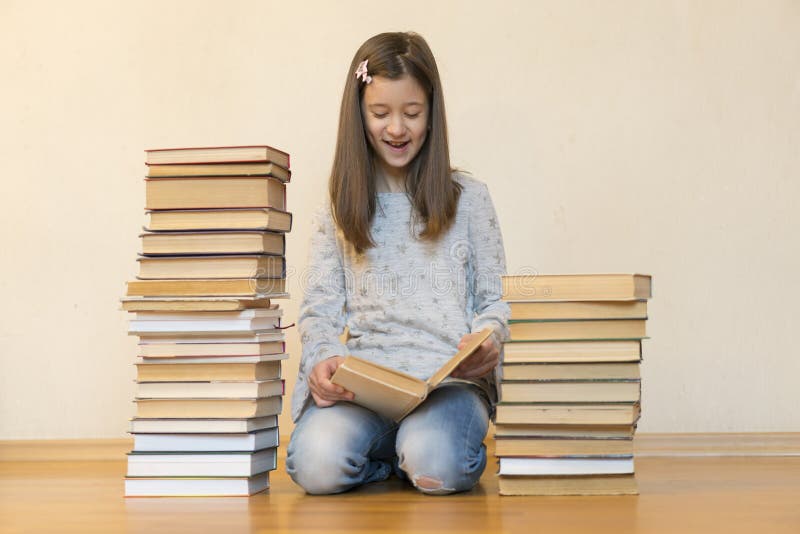 Girl reading a book sitting on the floor in an apartment. Cute girl reading book at home. education and school concept - little stock image Girl reading a book sitting on the floor in an apartment. Cute girl reading book at home. education and school concept - little stock image