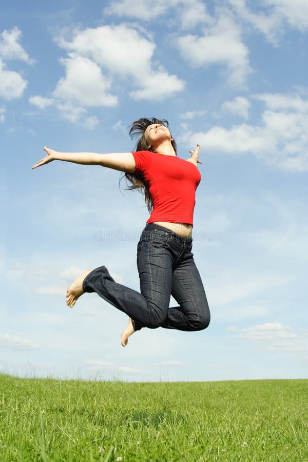 Girl in red shirt jumping on summer meadow
