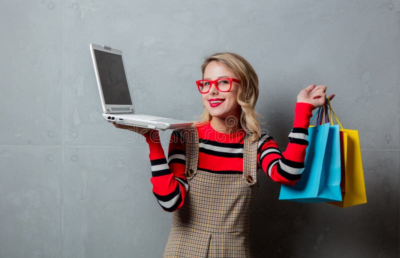 Girl in red striped sweater with shopping bags and laptop computer royalty free stock photo Girl in red striped sweater with shopping bags and laptop computer royalty free stock photo