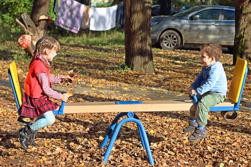 Girl in red vest and her brother on seesaw