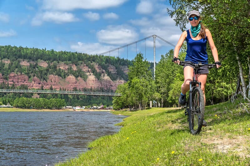 The girl rides bicycle on the river bank