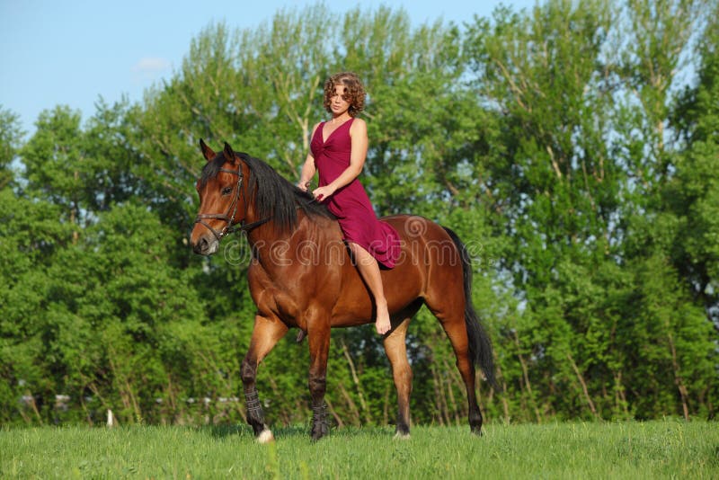 Girl riding on back of a German pony in a meadow