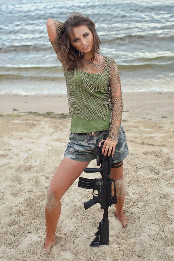 Girl with a rifle on the beach stock photos Girl with a rifle on the beach stock photos