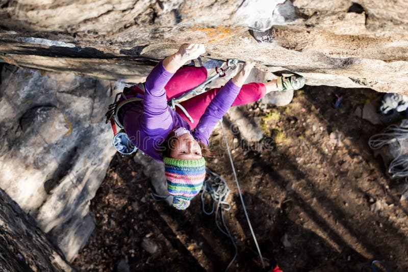 Girl rock climber climbs on the rock with the lower insurance men in colorful clothes and a hat in the fall stock images Girl rock climber climbs on the rock with the lower insurance men in colorful clothes and a hat in the fall stock images