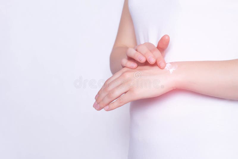 The girl rubs the healing ointment into the wrist joint against pain and inflammation in the joint, White background, copy space, stock photo The girl rubs the healing ointment into the wrist joint against pain and inflammation in the joint, White background, copy space, stock photo