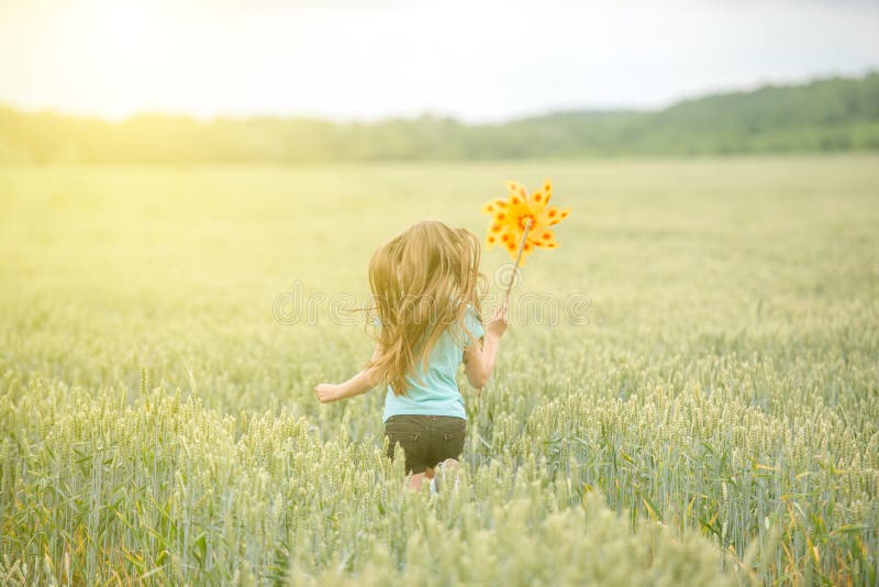 Girl running through field with pinwheel