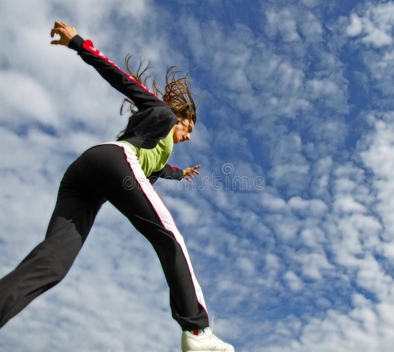 Giovane ragazza in esecuzione all'esterno in condizioni di cielo blu con cloudscape, visto da sotto.