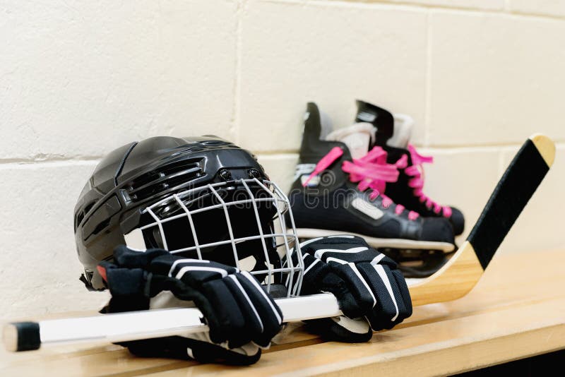 Girl`s hockey gear: helmet, gloves, sticks, skates with pink laces