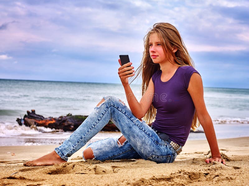 Girl on sand near sea call help by phone.