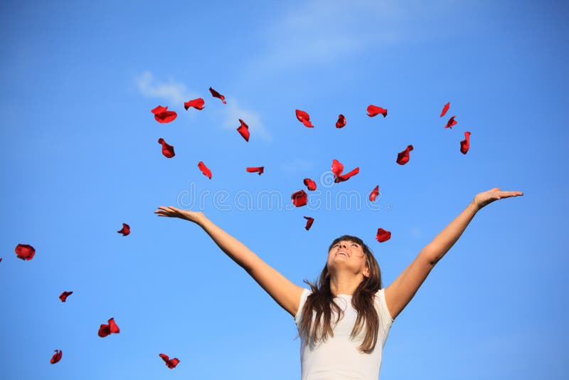 Girl scatters petals of rose against sky