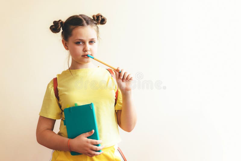 Girl of school age with a book, pen and school backpack in yellow sportswear