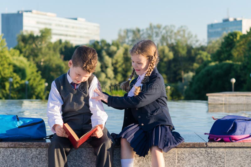 Girl in school uniform prevents a boy from reading a book royalty free stock photo Girl in school uniform prevents a boy from reading a book royalty free stock photo