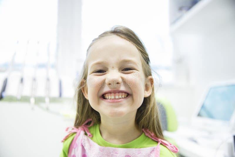 Girl showing her healthy milk teeth at dental office