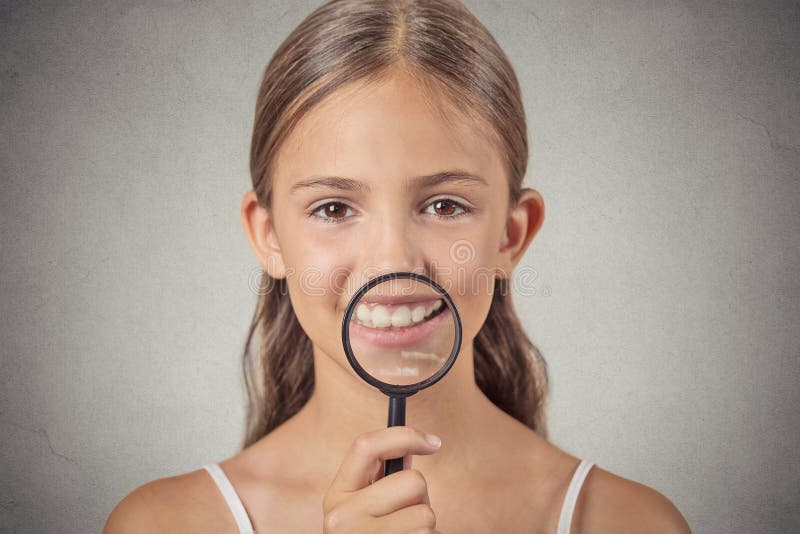 Girl showing teeth through a magnifying glass