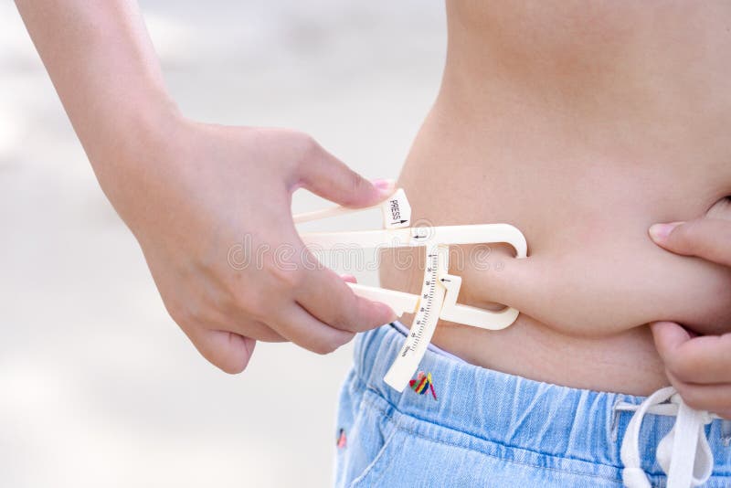 Girl shows holding and pushing the skin of the belly cellulite with personal body fat tester stock photos Girl shows holding and pushing the skin of the belly cellulite with personal body fat tester stock photos