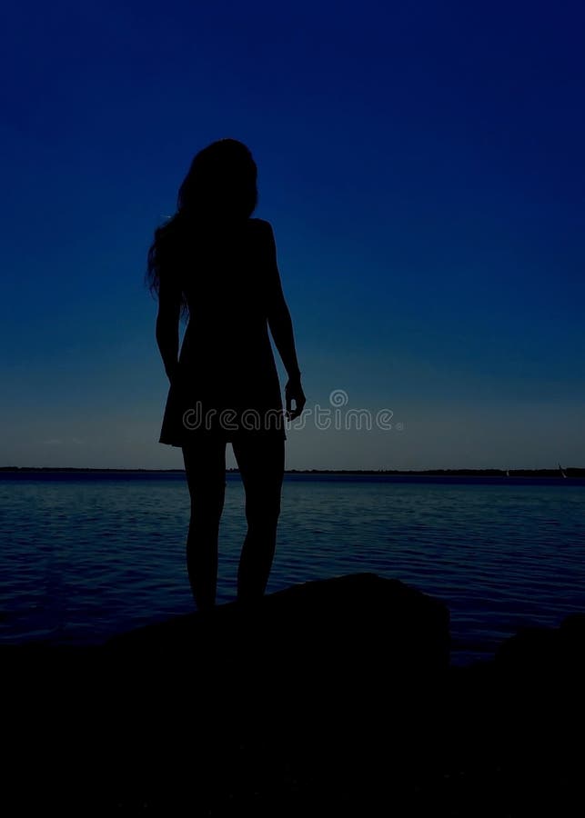 Girl silhouette, in blue hour. Girl standing on the lake coast royalty free stock image Girl silhouette, in blue hour. Girl standing on the lake coast royalty free stock image