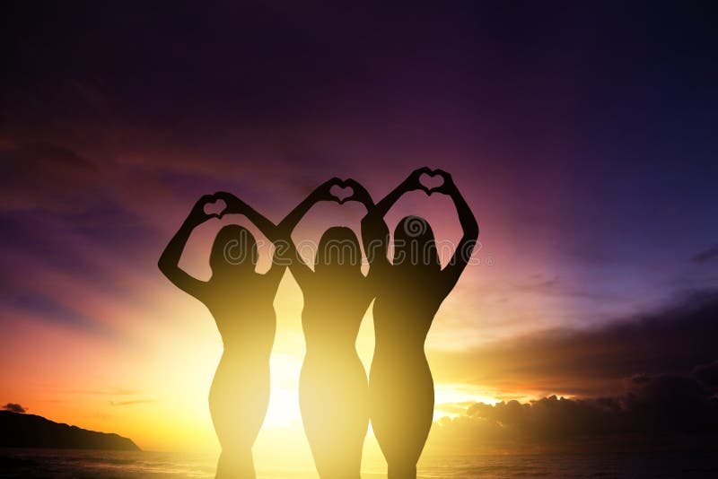 Girl silhouettes hands making heart shape with sunset background stock photos