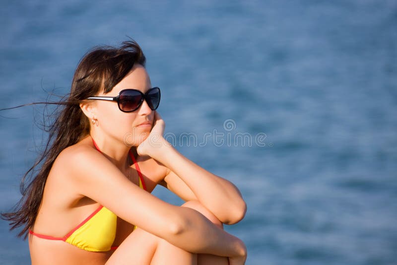 Girl sits on the beach of the blue sea