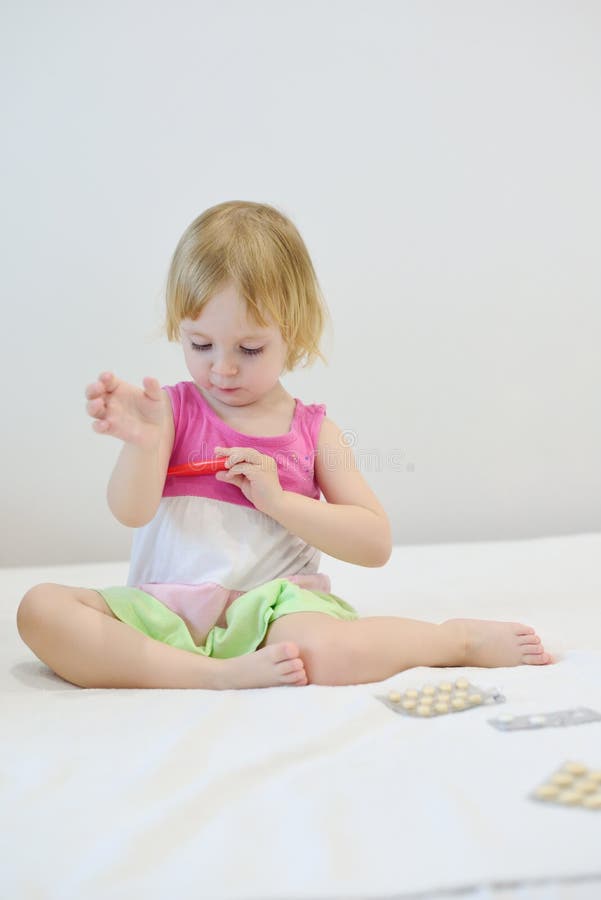 The girl is sick and is taking her temperature royalty free stock photography