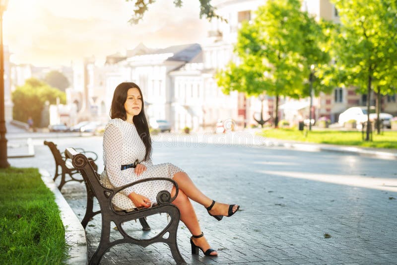 A girl sits on a bench in the center of the old city in the early morning. Odessa. Ukraine.