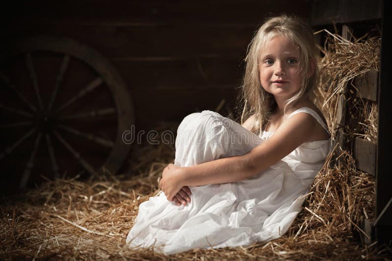 Girl sits on hay in the barn