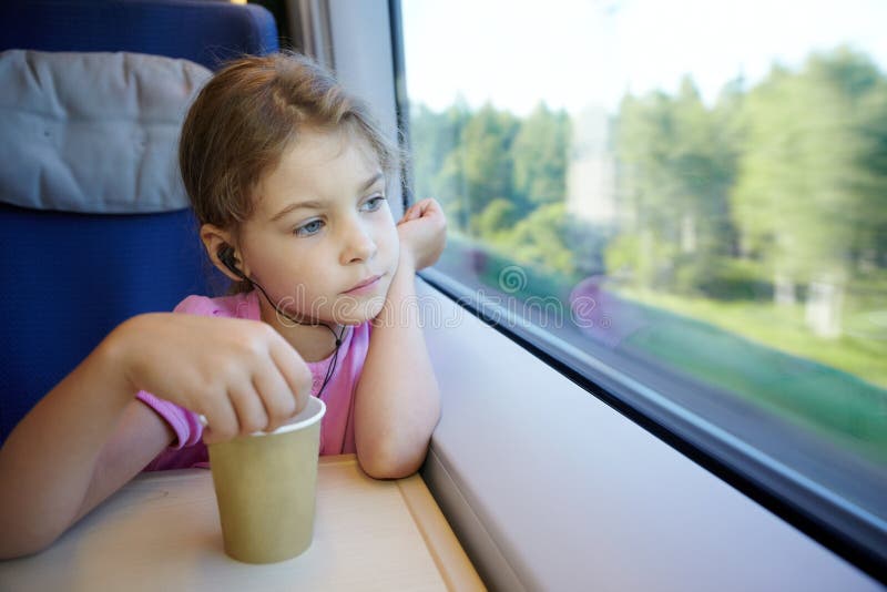 Girl sits near window in moving high-speed train