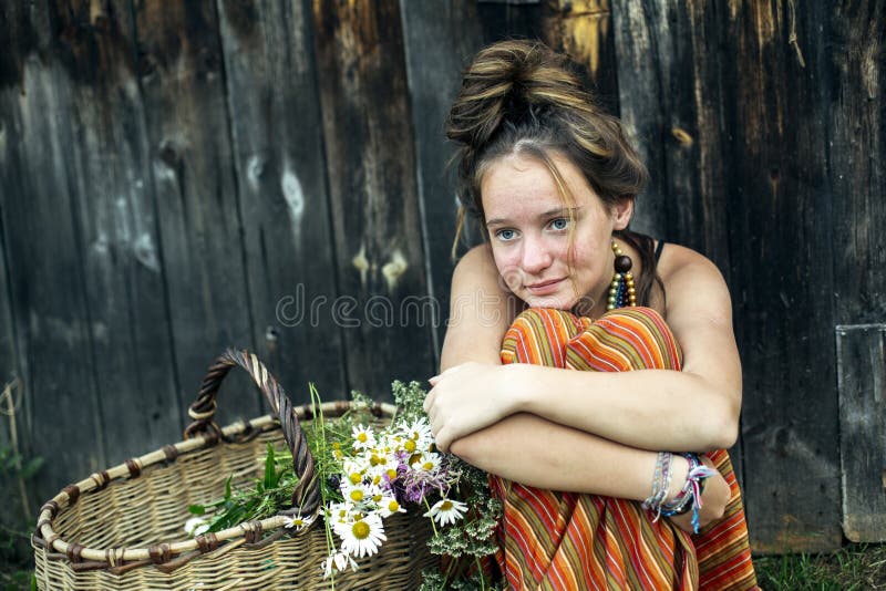 A Girl is Sitting with a Basket of Flowers in the Village Outdoors ...
